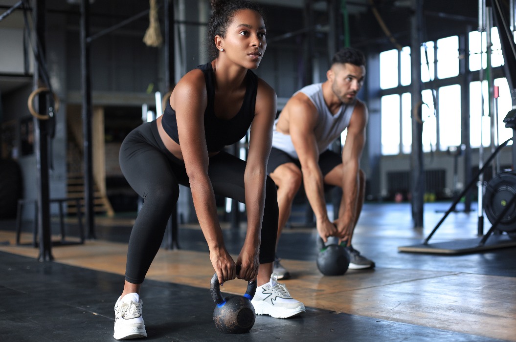 Ein durchtrainiertes und muskulöses Paar konzentriert sich während eines Trainingskurses im Fitnessstudio auf das Heben einer Hantel.