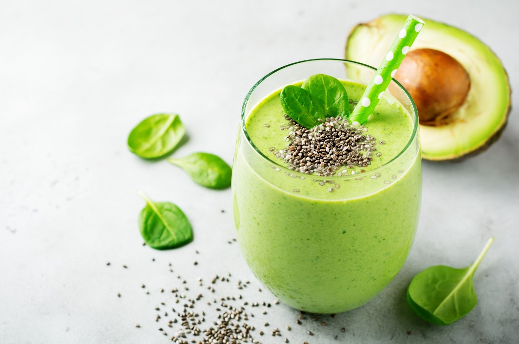 Vegetarischer, gesunder grüner Smoothie aus Avocado, Spinatblättern, Apfel und Chiasamen vor grauem Betonhintergrund. Selektiver Fokus. Platz für Text.