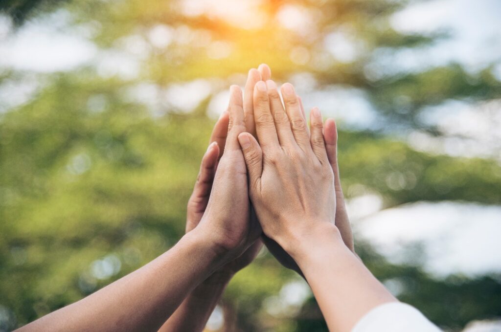 Teamwork-High-Five, während das Team gemeinsam ein energiegeladenes Luftgrußzeichen macht